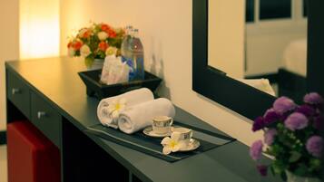 Habitación de hotel con un mostrador de baño ordenado, una toalla, una taza y una bandeja con flores.