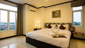 Quarto de hotel com uma cama grande, um quadro na parede e vista da cidade pelas janelas.