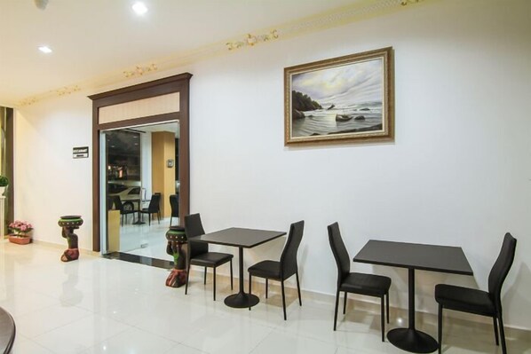 Un comedor con dos mesas y sillas, un cuadro en la pared, y una puerta que da a otra habitación.