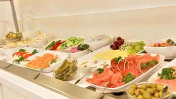 A buffet with various food items including meats, cheeses, and fruits.