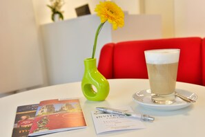 A table with a glass of beer, a pen, a brochure, and a vase with a flower. - INVITE Hotel Fulda City (Fulda)