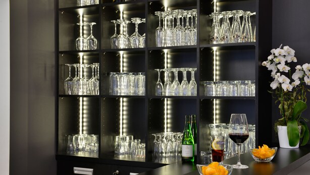 Una zona de bar con múltiples estantes llenos de vasos y botellas.