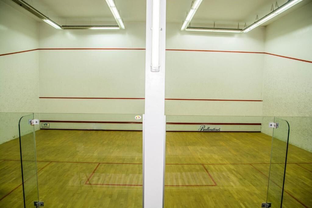 Ein Squashplatz mit Glaswänden und Holzboden, markiert mit roten Linien.