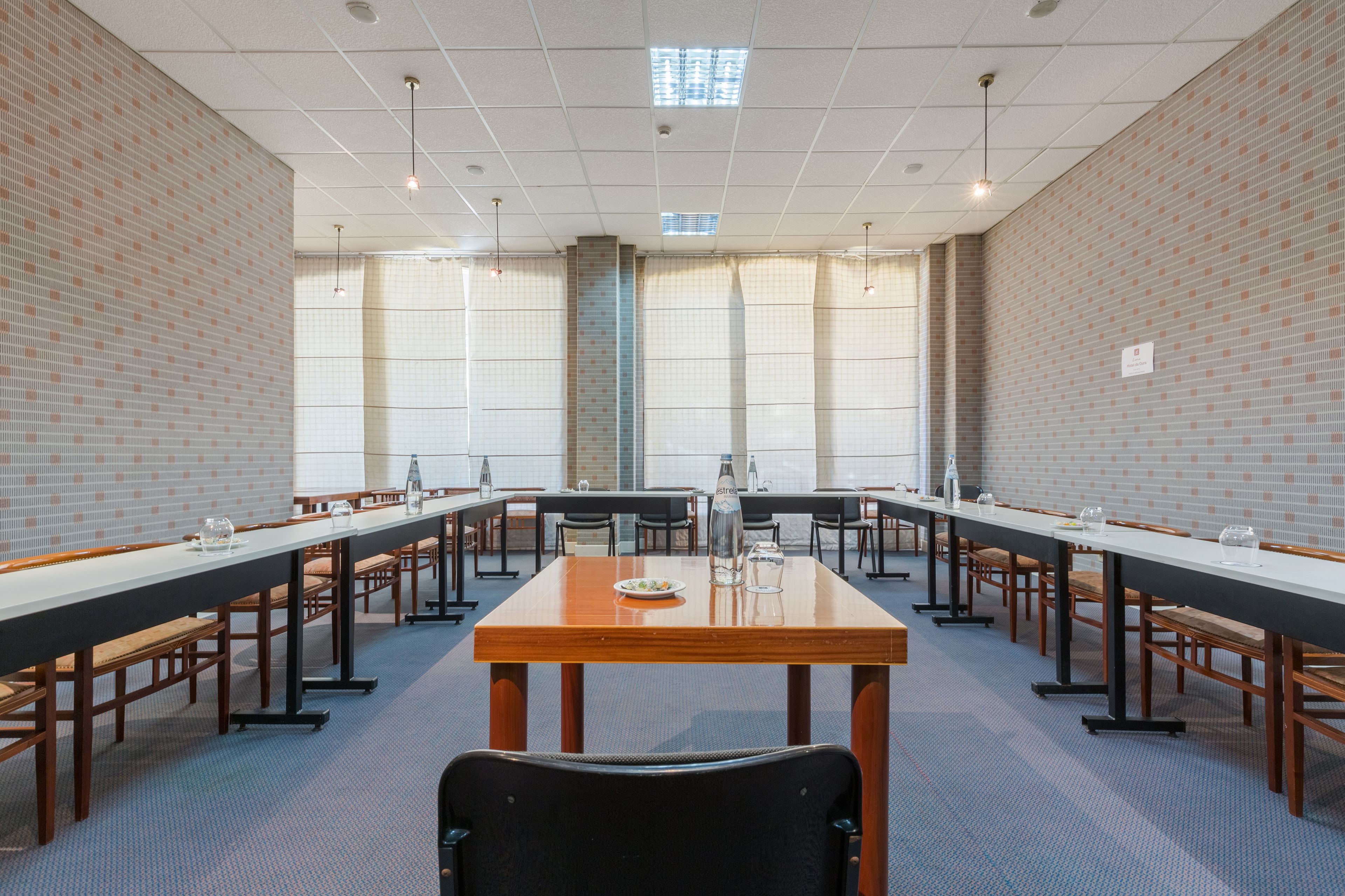 Ein Konferenzraum mit einem langen Tisch, Stühlen und einer Projektionsleinwand.