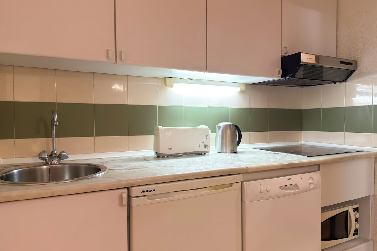 A kitchen with a sink, a toaster, a kettle, a dishwasher, and a microwave.