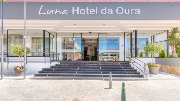 Hotel Luna da Oura met een moderne ingang, glazen gevel en treden die naar de ingang leiden.
