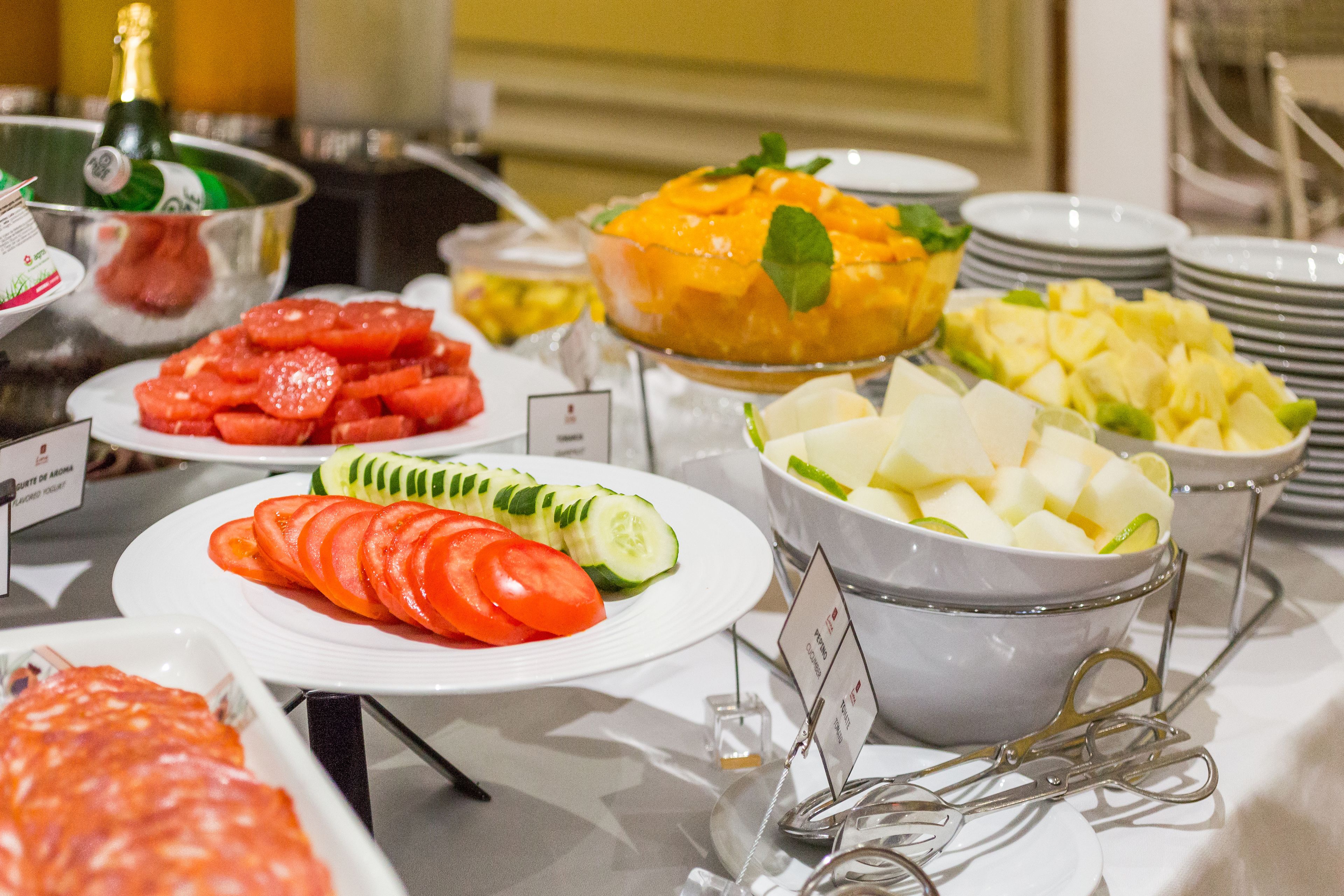 A buffet with various fruits and vegetables, including watermelon, tomatoes, cucumbers, and pineapple.