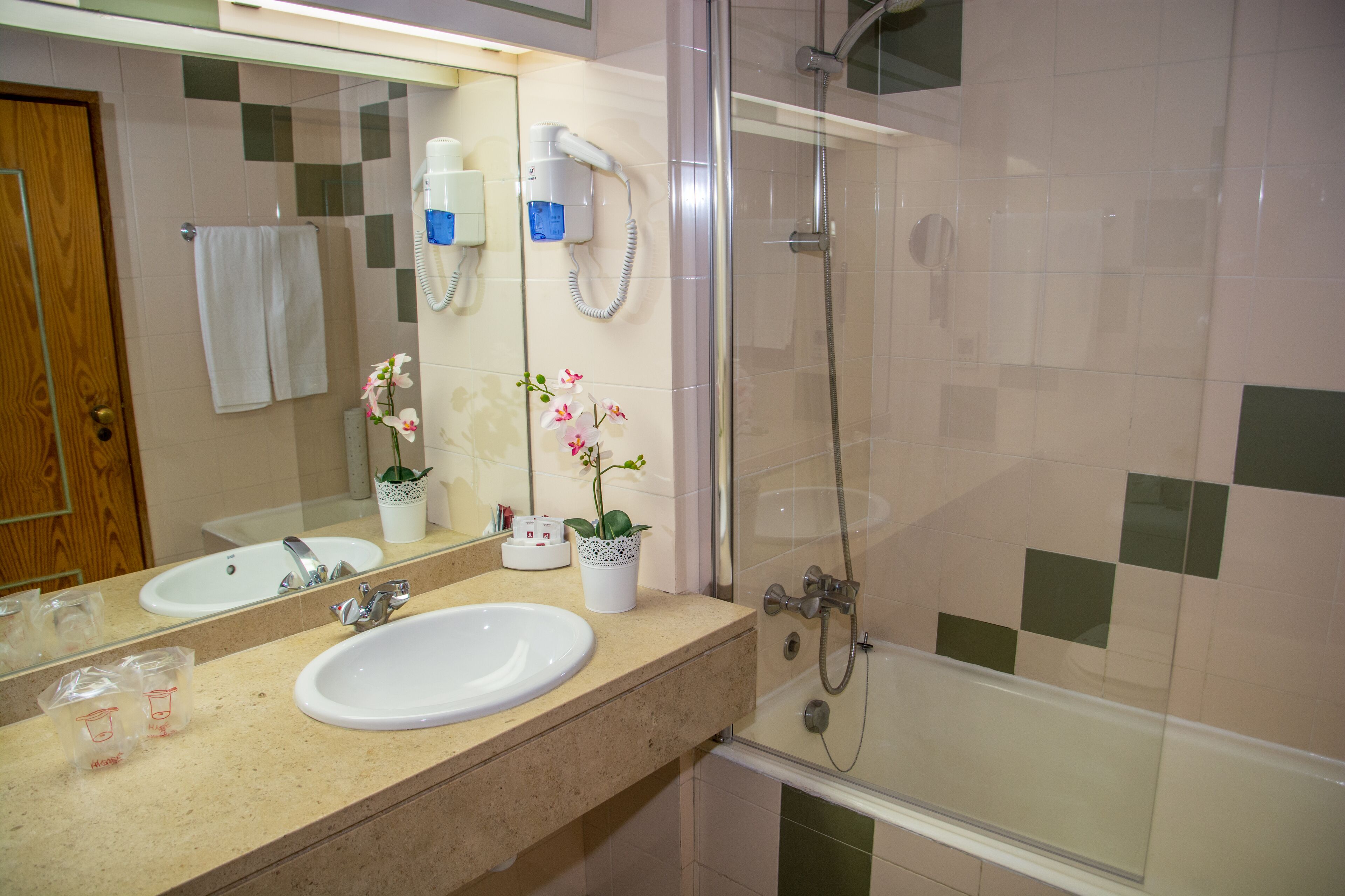 A bathroom with a sink, mirror, and shower.