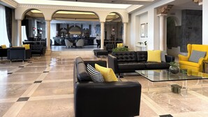 Een ruime lobby met een bar, leren banken en een glazen salontafel.