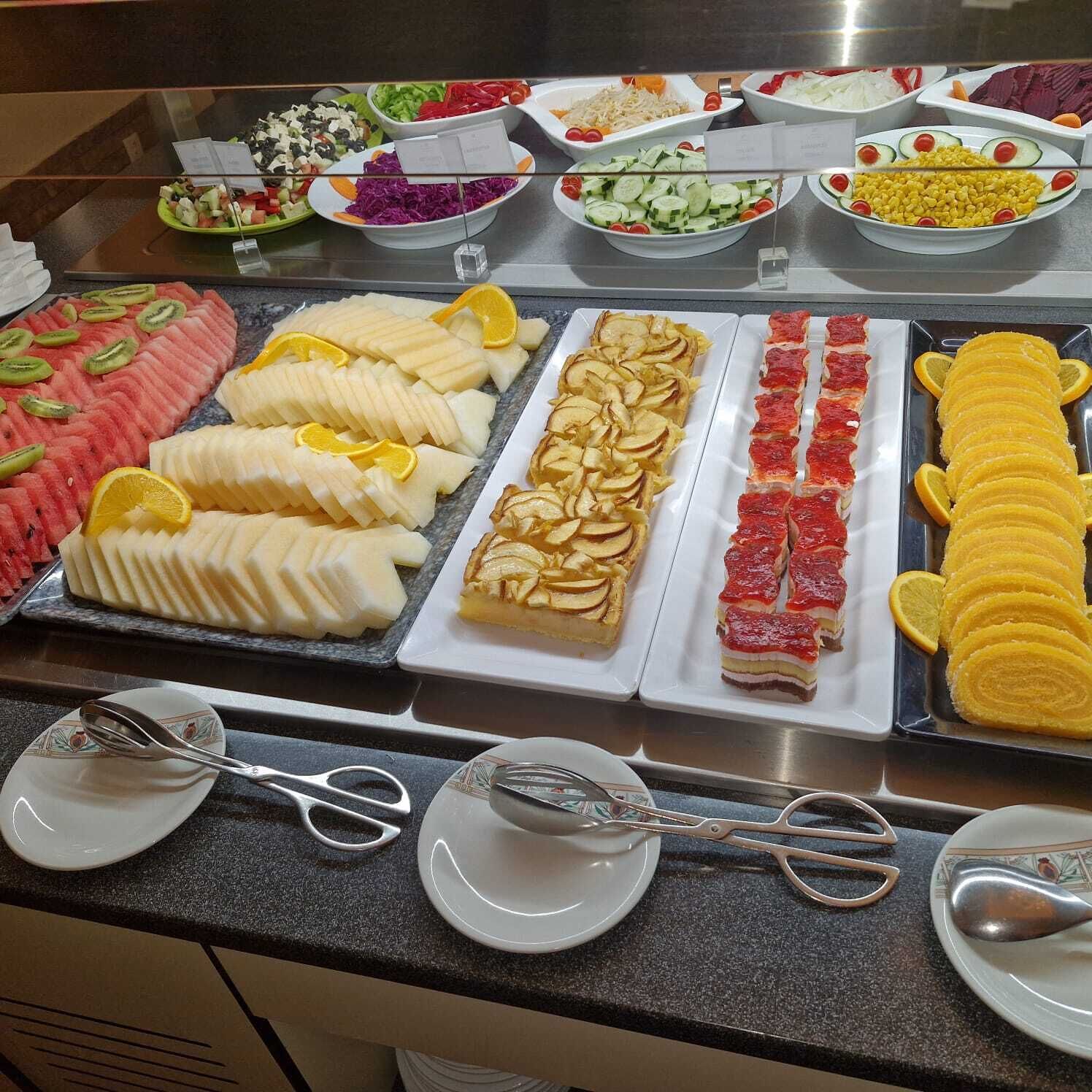 Ein reichhaltiges Buffet mit einer Auswahl an Speisen, darunter Obst, Salate und Desserts.