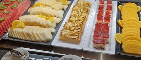 Un bufé con diversas opciones de comida, como frutas, ensaladas y postres.