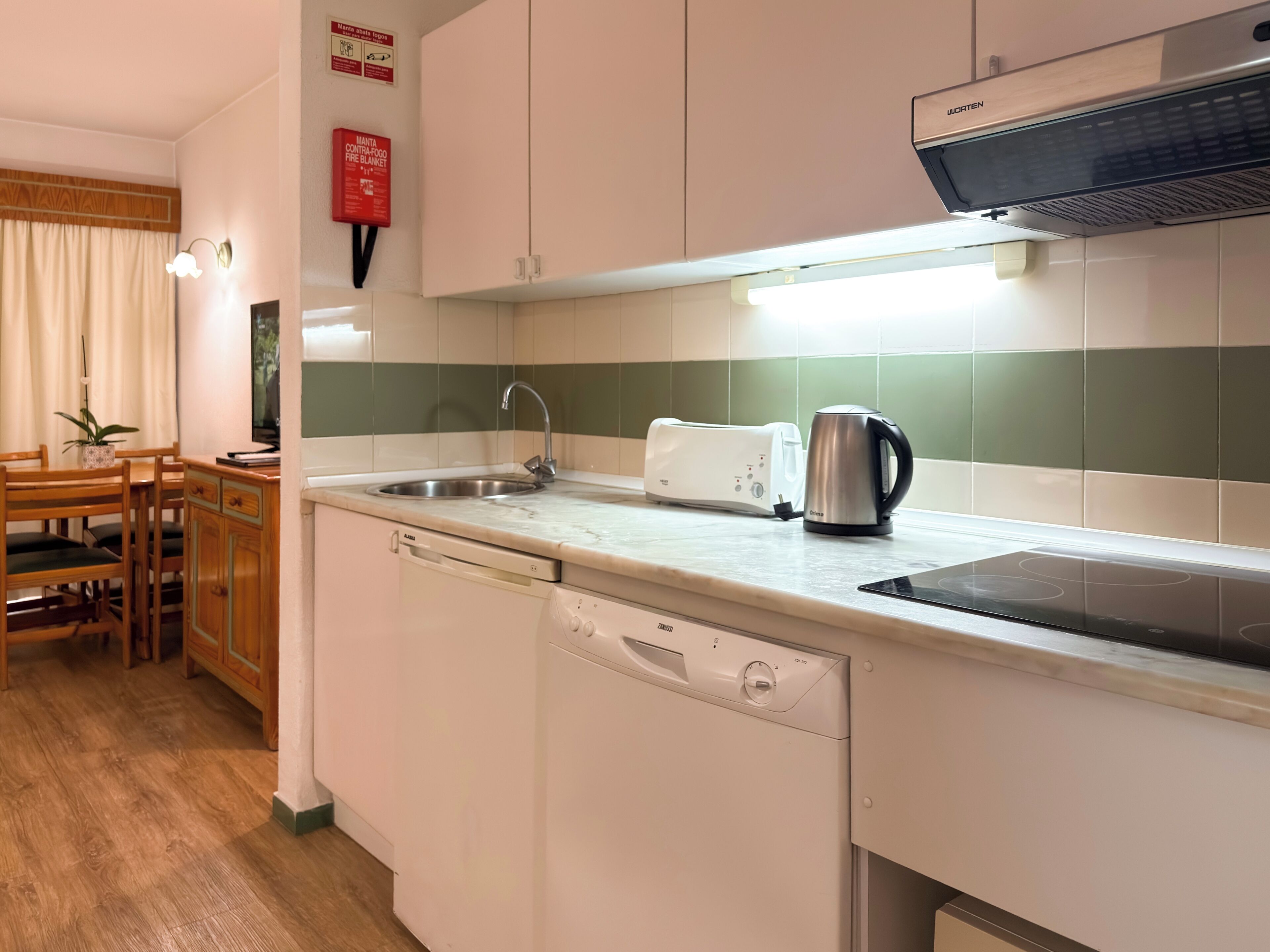 A kitchen with a sink, a toaster, a kettle, and a dishwasher.