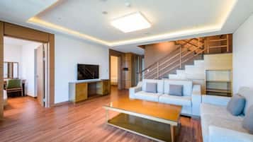 Una sala de estar moderna con una escalera, piso de madera y un televisor de pantalla plana.