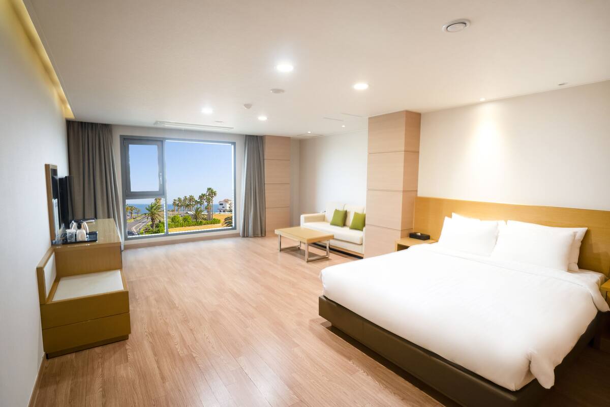 Une chambre d’hôtel moderne équipée d’un grand lit, d’un canapé, d’une table basse et d’un téléviseur.