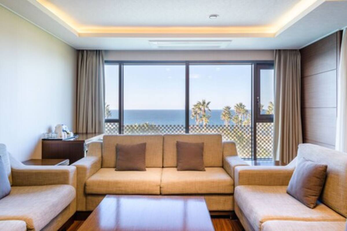 Un salon moderne avec un ensemble de canapés, une table basse et une vue sur la mer grâce à de grandes fenêtres.