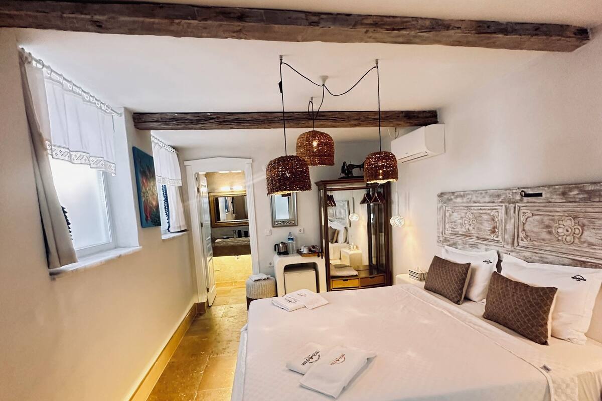 A spacious bedroom with a large bed, a wooden ceiling, and a modern chandelier.