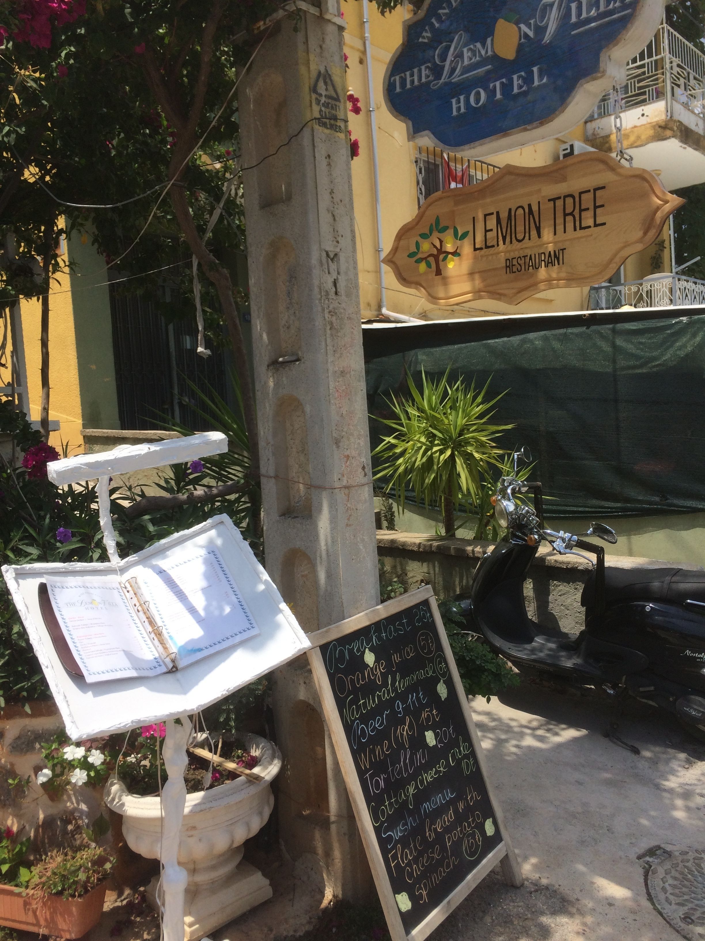 A signboard for Lemon Tree Restaurant with a menu listing breakfast items like orange juice, beer, wine, and various dishes.