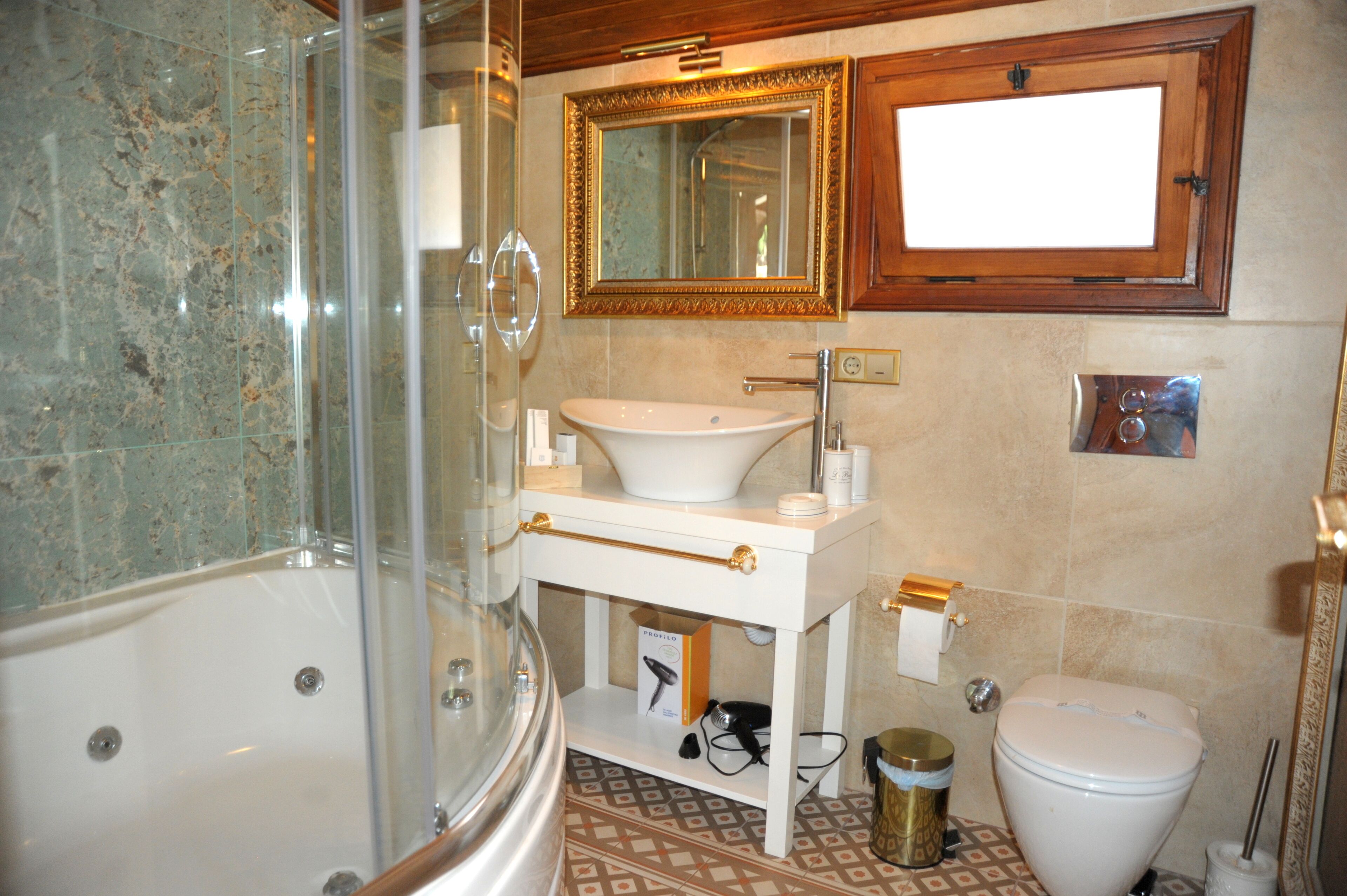 A bathroom with a glass shower enclosure, a white sink, a toilet, and a vanity with a mirror above it.