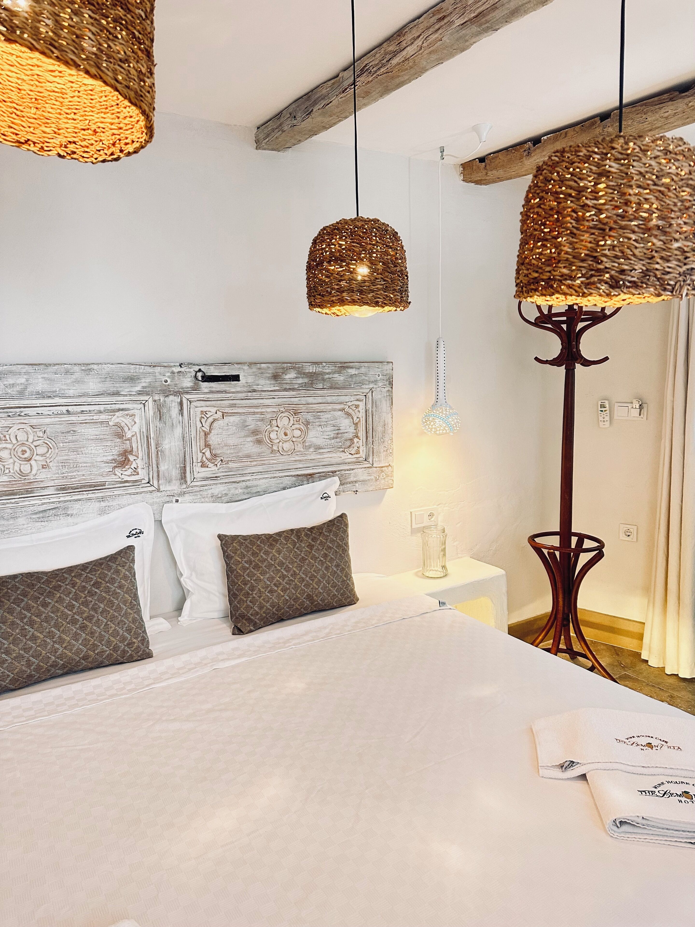 A bedroom with a bed, two bedside tables, a decorative headboard, and hanging lamps.