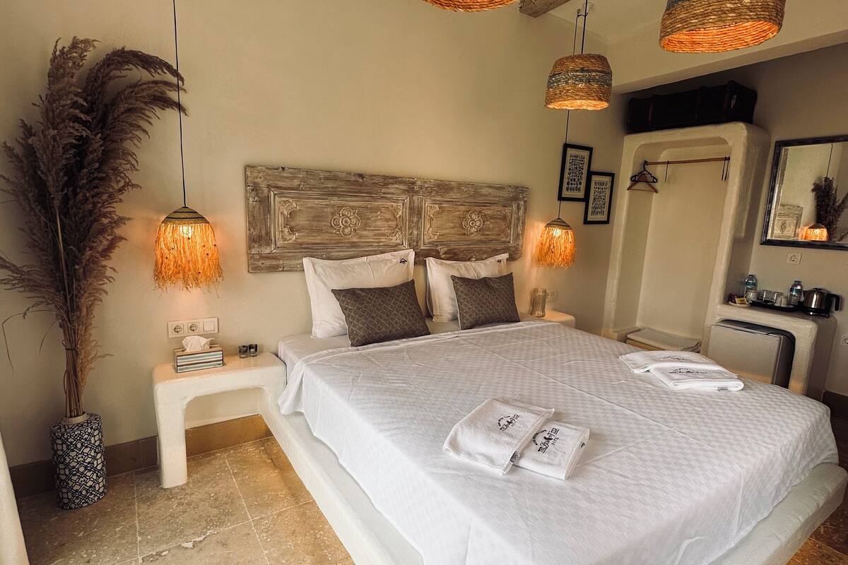 A spacious bedroom with a large bed, two bedside tables, and three hanging wicker lamps.