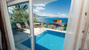 Un balcón con piscina, con vistas panorámicas del mar y las montañas.