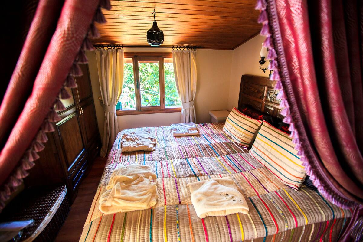 A bedroom with a bed, curtains, a window, and a lamp.