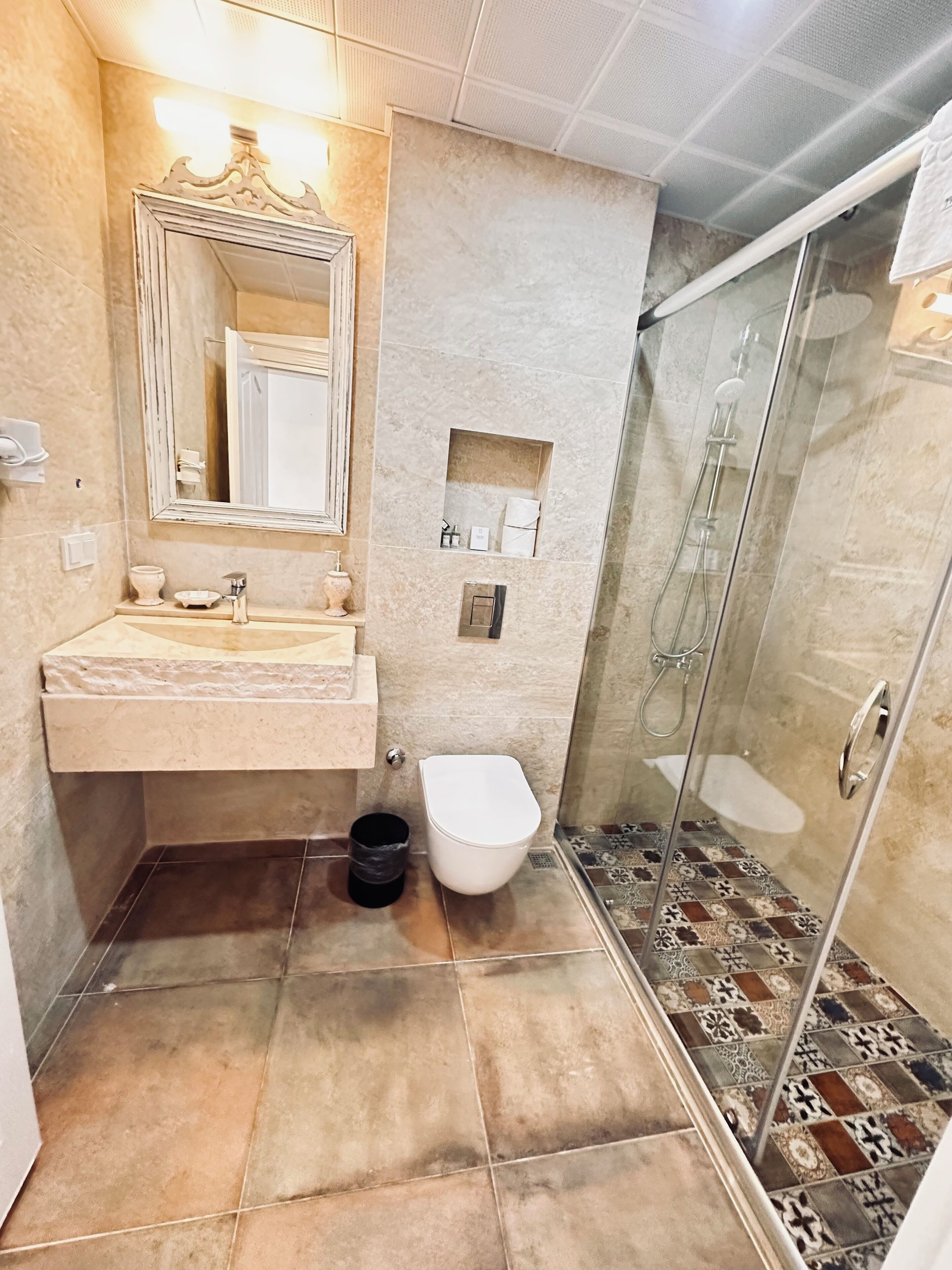 Un baño con lavamanos, espejo, inodoro y ducha.