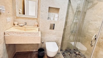 Un baño con lavamanos, espejo, inodoro y ducha.