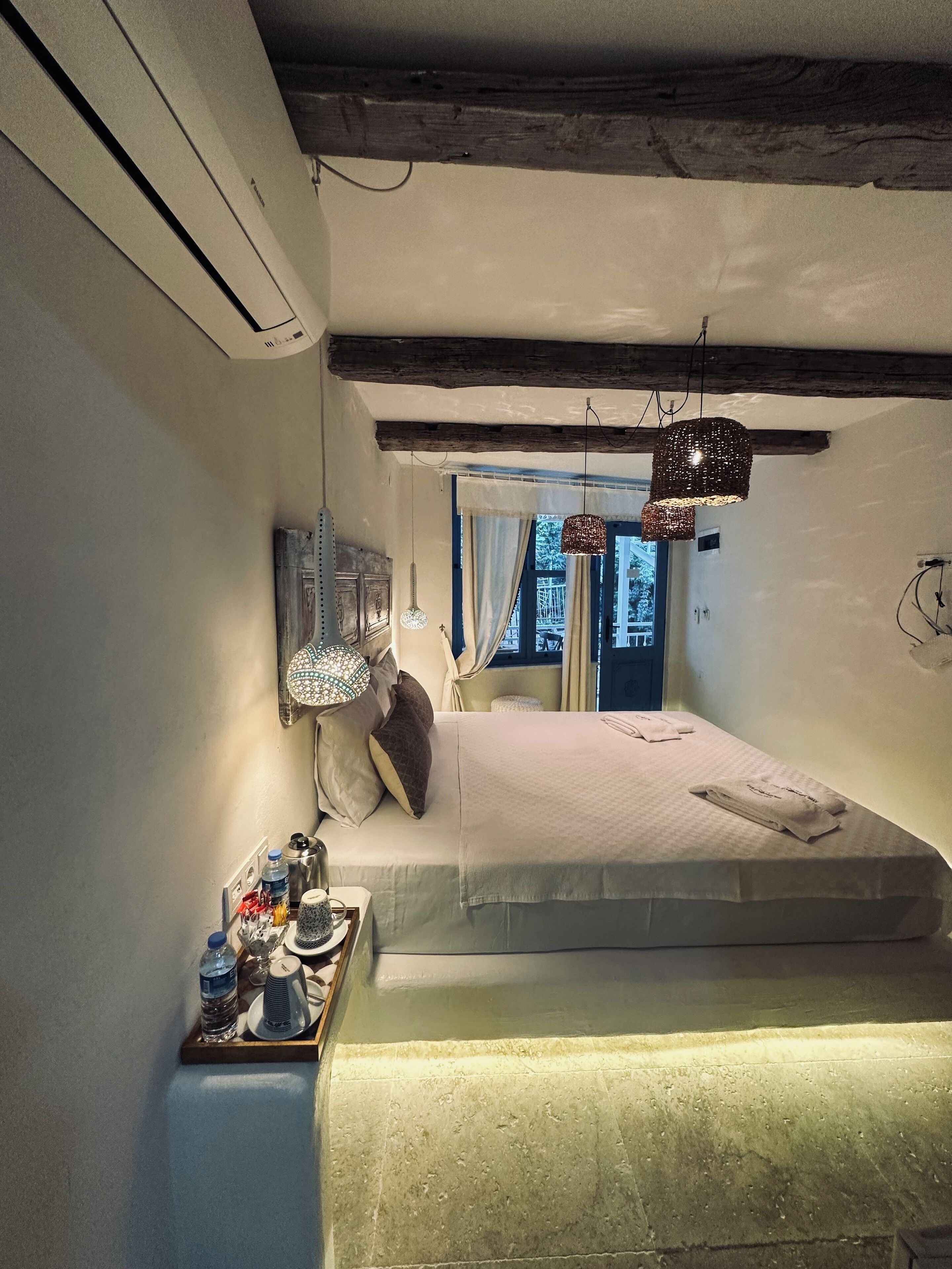 A compact bedroom with a bed, bedside table, and a window with curtains.