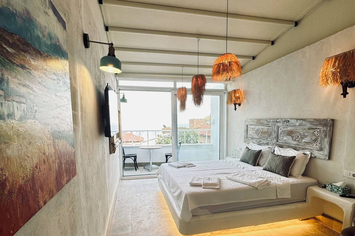 A modern bedroom with a large bed, a view to the outside, and a unique wall art piece.