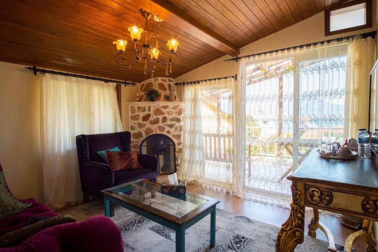 A cozy living room with a stone fireplace, a comfortable sofa, a glass coffee table, and a wooden ceiling.
