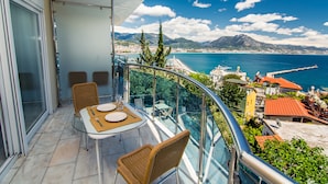 A balcony with a table and chairs, overlooking a coastal city with mountains in the background. - Lemon Villa Hotel - Adult Only (Alanya)