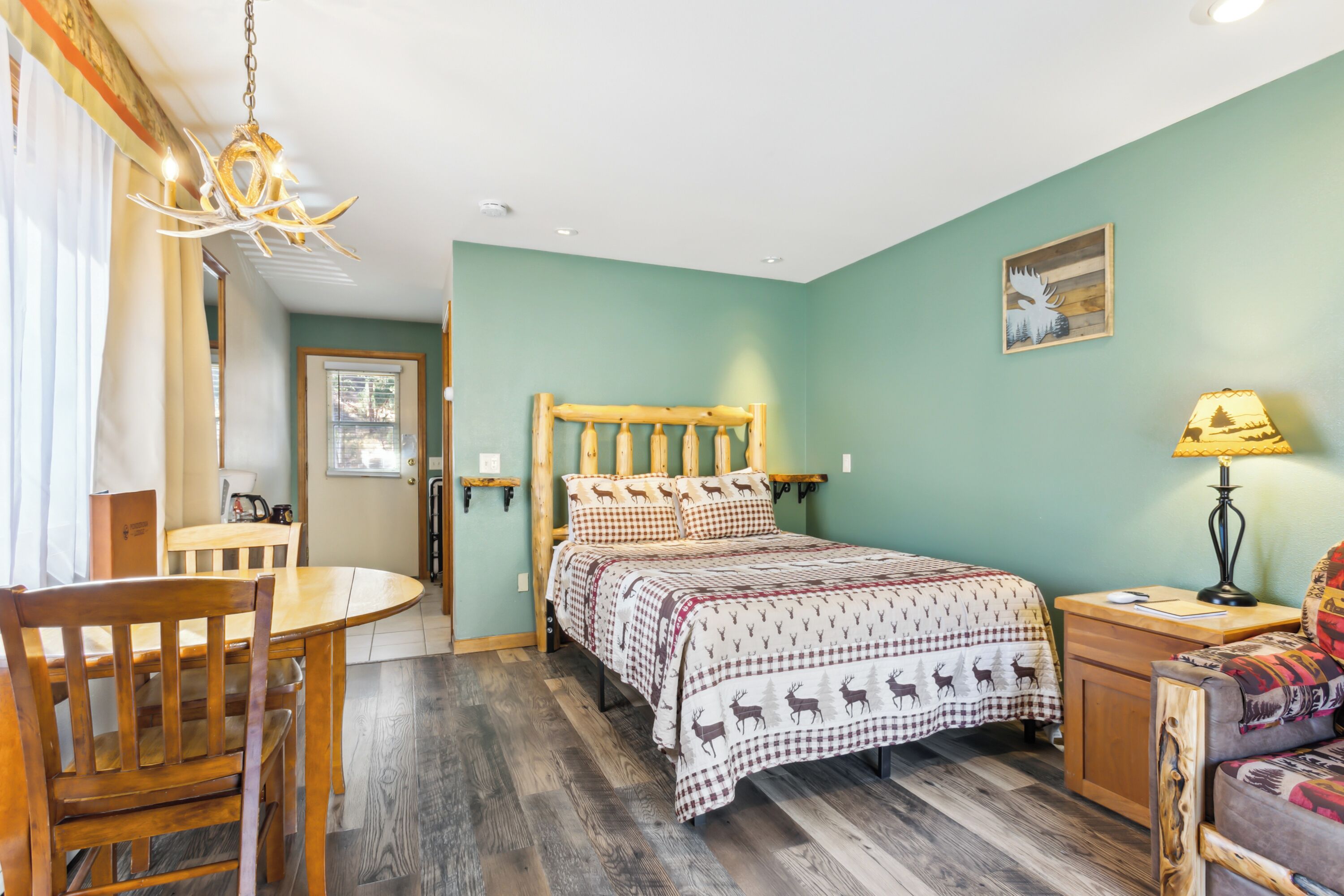 A cozy room with a bed, a wooden headboard, a dining table, and a chair.