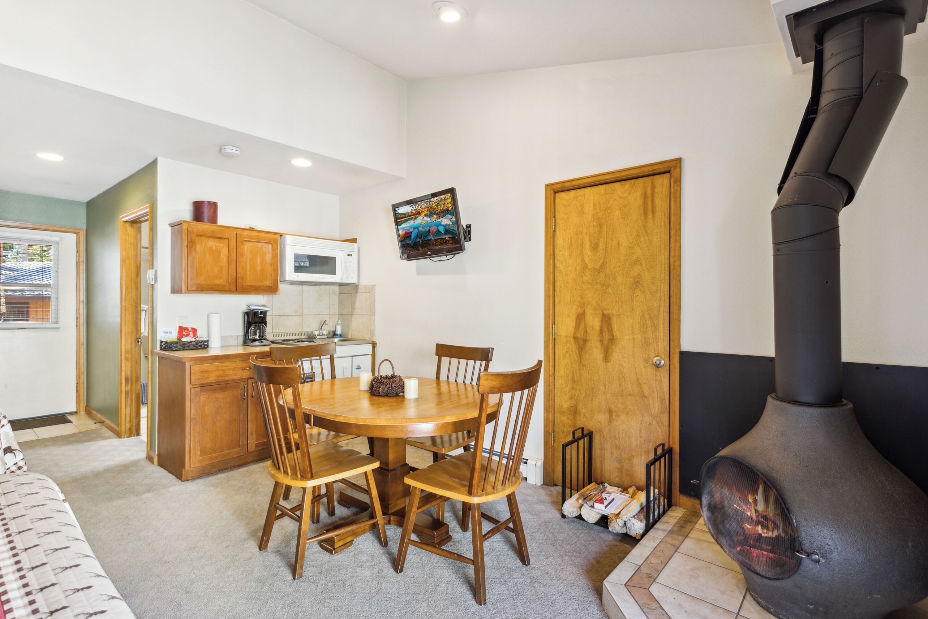 A compact kitchen with wooden cabinets, a microwave, and a dining table with chairs.