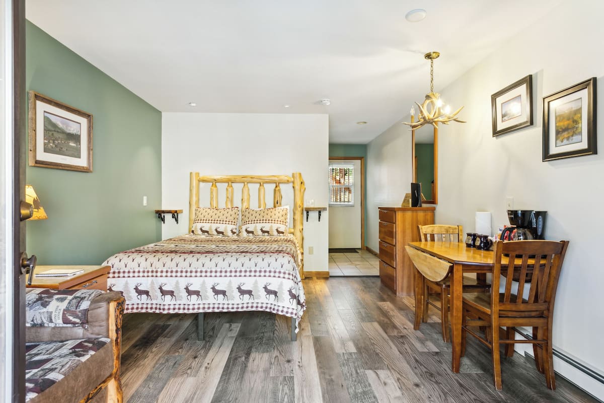 Una camera da letto con un letto di legno, un tavolo da pranzo, sedie, un lampadario e quadri appesi al muro.