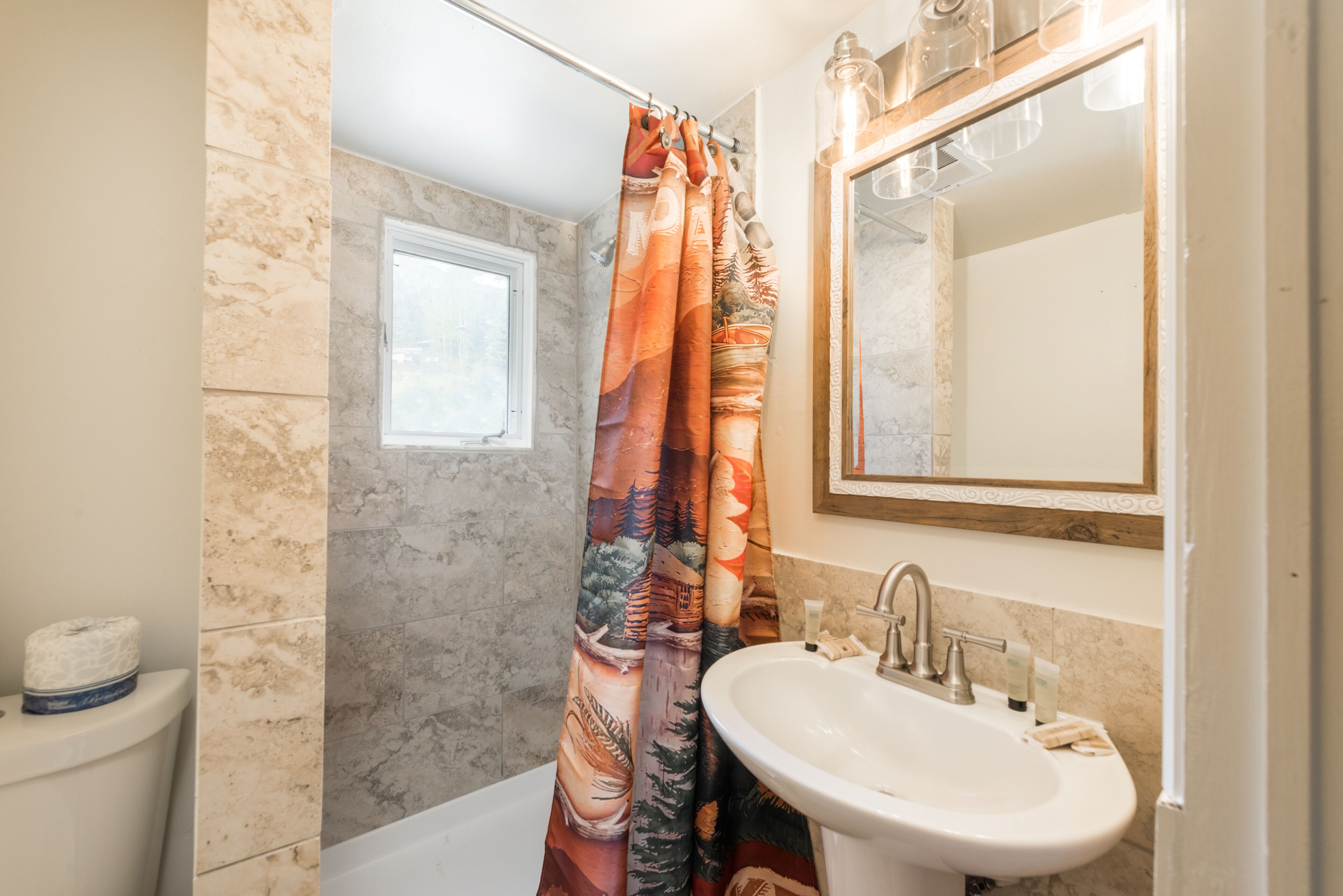 A bathroom with a shower curtain, a sink, and a mirror.