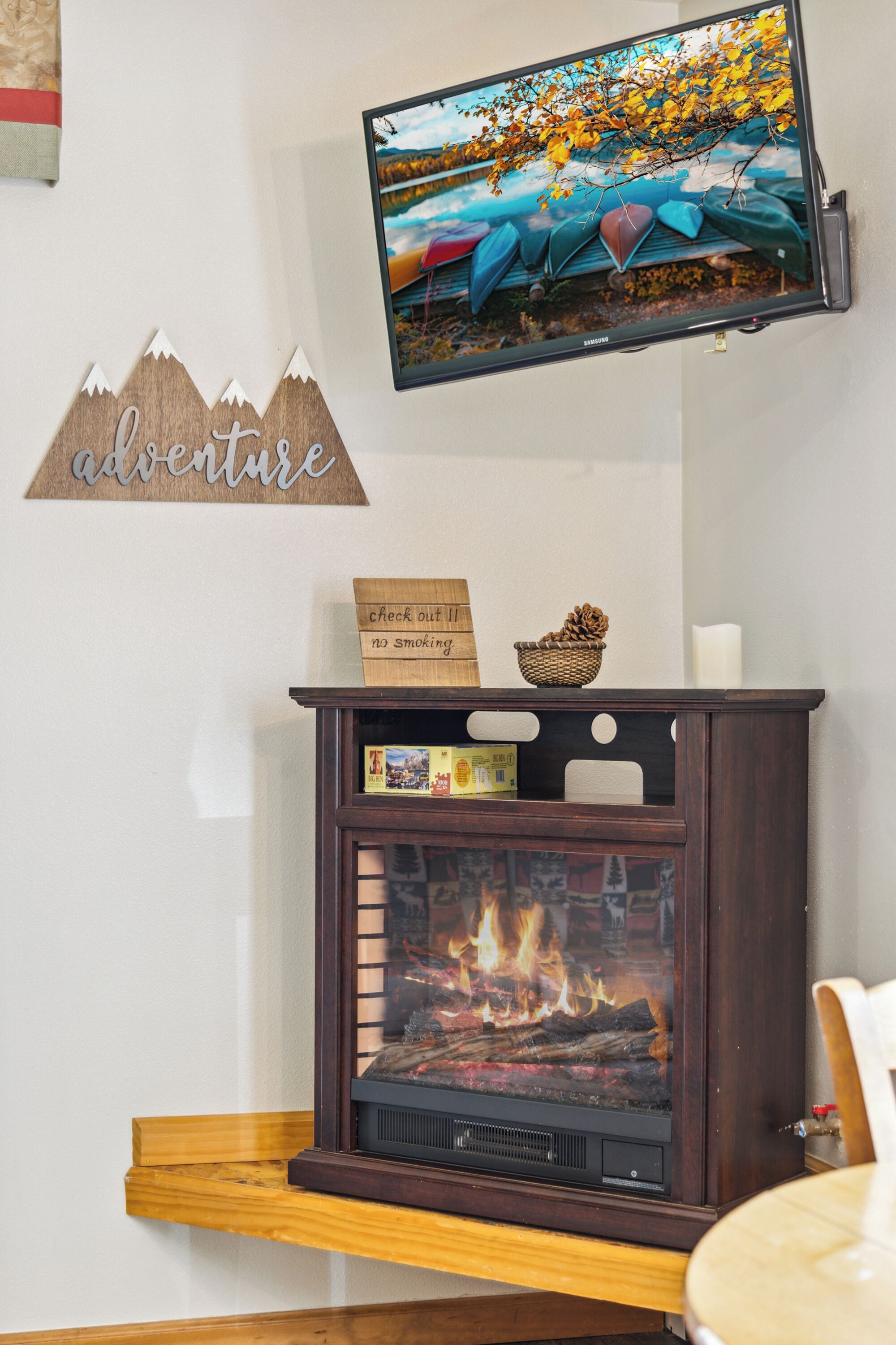 A fireplace with a TV mounted above it, a sign on the mantel, and a wall decoration.