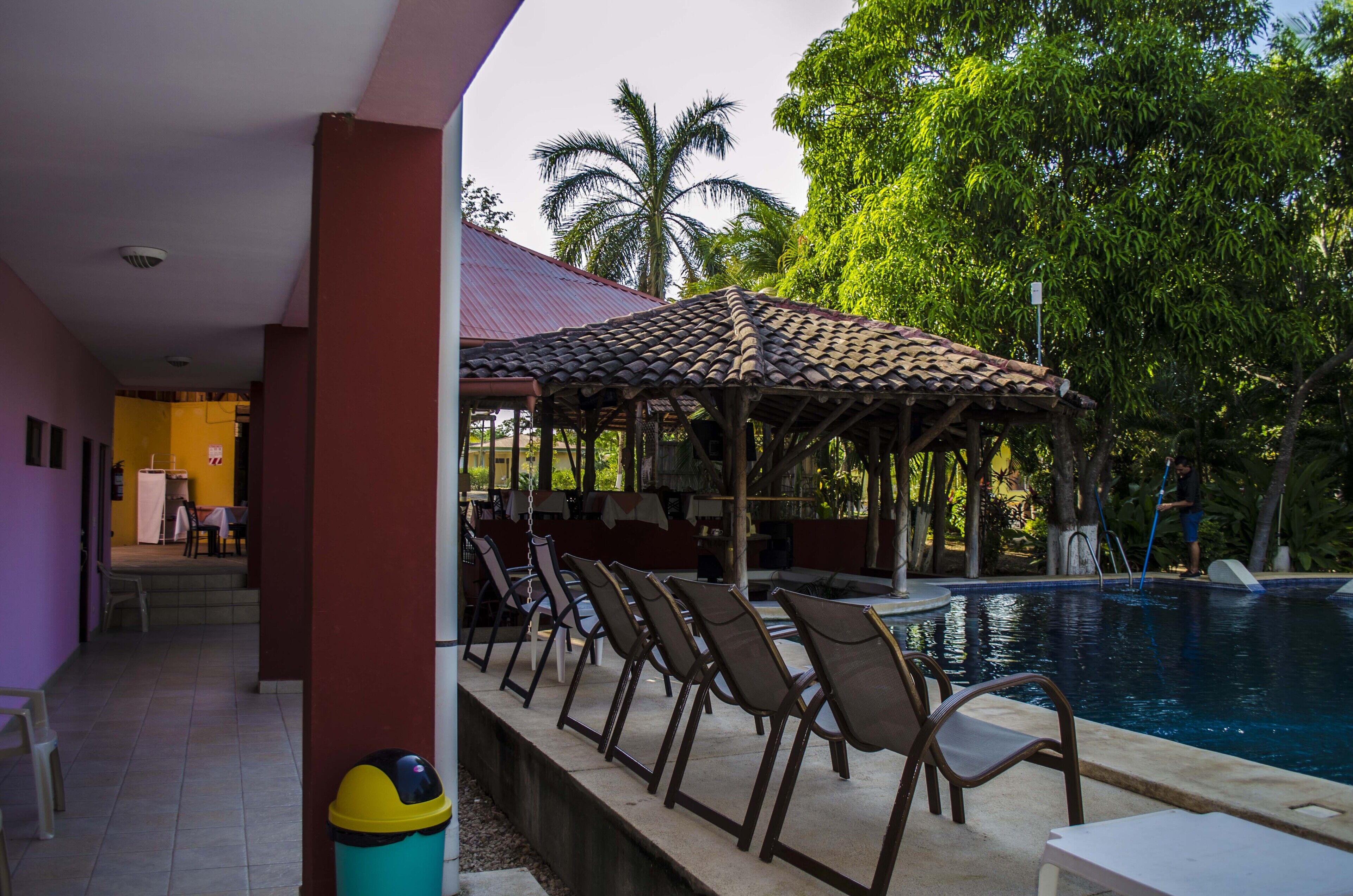 A pool area with lounge chairs and a covered seating area.