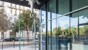 Un intérieur moderne agrémenté d’un lustre blanc, de grandes fenêtres et d’une façade en verre qui reflète le paysage urbain.