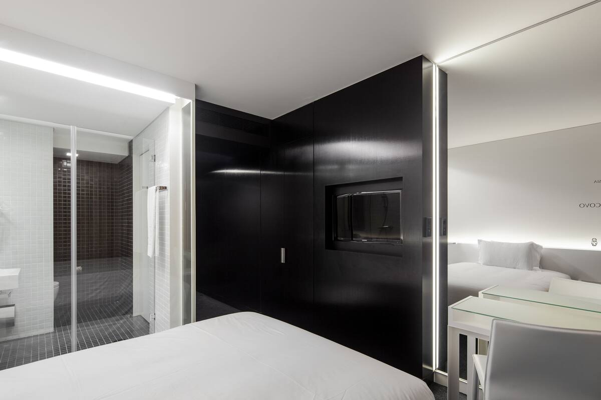 Et moderne hotelværelse med seng, skrivebord med glasplade og et stort spejl.