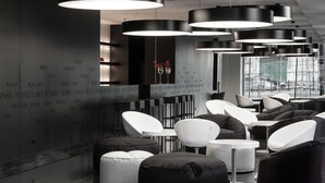 Un espace de détente moderne offrant de nombreuses options d’assises, notamment des canapés et des fauteuils, ainsi qu’un mur sur lequel figurent différents noms de villes.