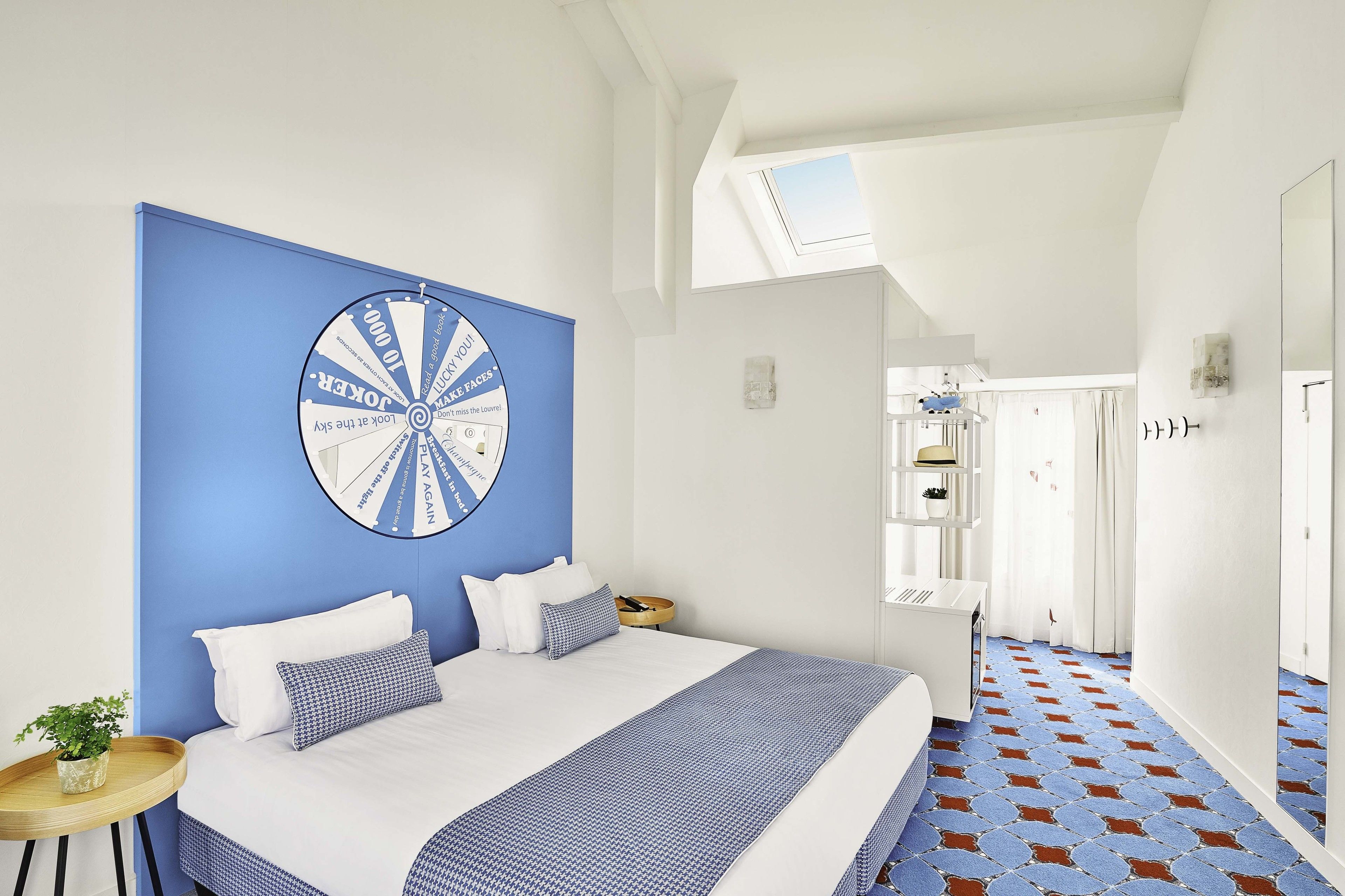Ein Schlafzimmer mit einem großen Bett, einer blauen Akzentwand, einem Deckenventilator und Blick auf einen Flur.