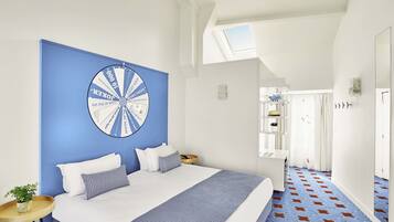 Ein Schlafzimmer mit einem großen Bett, einer blauen Akzentwand, einem Deckenventilator und Blick auf einen Flur.