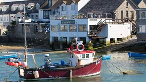 A red and white fishing boat named SC1 docked in a harbor with buildings in the background.