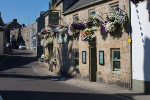 Un edificio de piedra con macetas colgantes de flores y un letrero que dice “Atlantic Restaurant.”