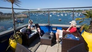 A balcony with wicker furniture overlooking a marina with boats.