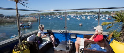 A balcony with wicker furniture overlooking a marina with boats.