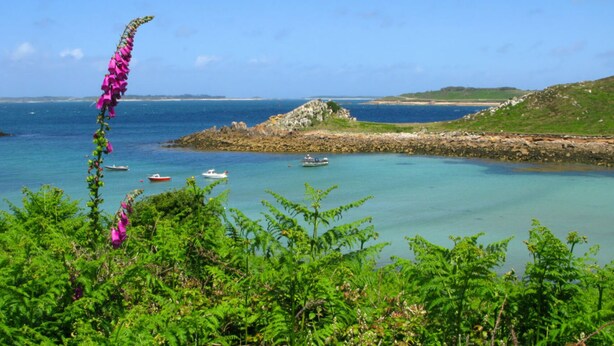 A coastal landscape with clear turquoise waters, boats, and rocky terrain.