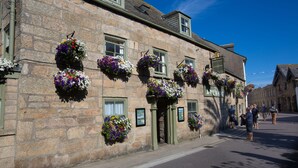 A stone building with multiple flower baskets hanging from the windows.