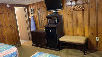 Une chambre d’hôtel avec deux lits, une télévision, un four à micro-ondes, une commode et un banc.